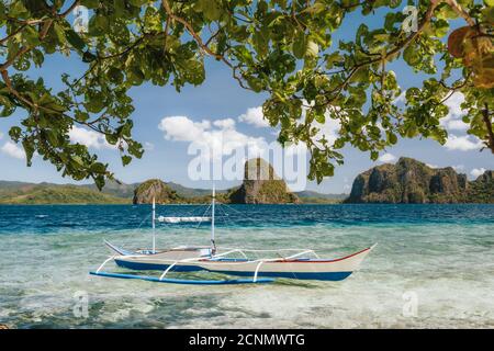 Banca Boot in flachem blauem Wasser auf Ipil Strand von Pinagbuyutan Island, El Nido, Palawan, Philippinen. Stockfoto