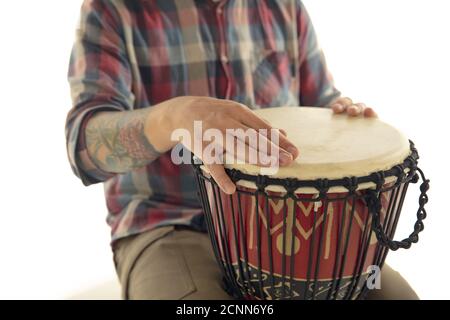Mann spielt ethnische Trommel Darbuka Percussion, Nahaufnahme Musiker isoliert auf weißem Studio Hintergrund. Männliche Hände klopfen Djembe, Bongo im Rhythmus. Musikalische handgemachte Instrumente, Weltkultur-Sound. Stockfoto