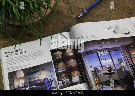 Viersen, Deutschland - August 18. 2020: Blick auf isolierten offenen Ikea-Katalog auf Holztisch mit Bleistift und Pflanze (Fokus auf der rechten Seite) Stockfoto