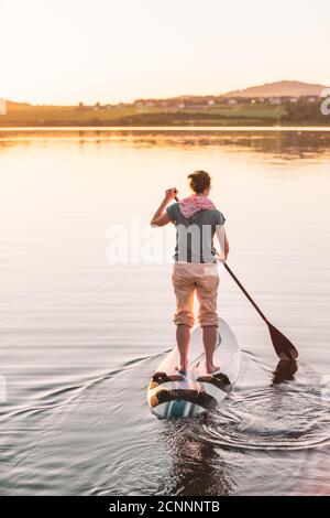 Junge Frau steht auf Paddleboarding bei Sonnenuntergang, Wallersee, Flachgau, Salzburg, Österreich Stockfoto