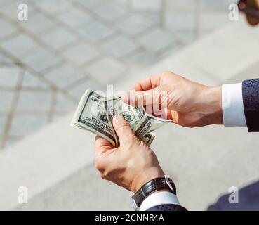 Die Hände der Männer halten Dollar. Erfolgreicher Geschäftsmann hält Gehalt.männliche Arme mit Uhr, Nahaufnahme. Hochwertige Fotos Stockfoto