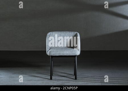 Bequemer weißer Ohrensessel in einem Studio mit grauen Wänden Stockfoto