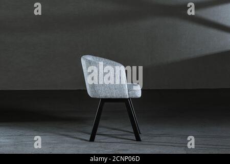 Bequemer weißer Ohrensessel in einem Studio mit grauen Wänden Stockfoto