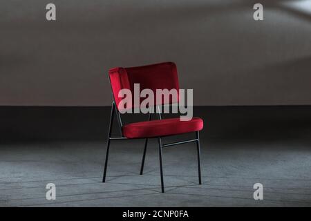 Bequemer roter Ohrensessel in einem Studio mit grauen Wänden Stockfoto