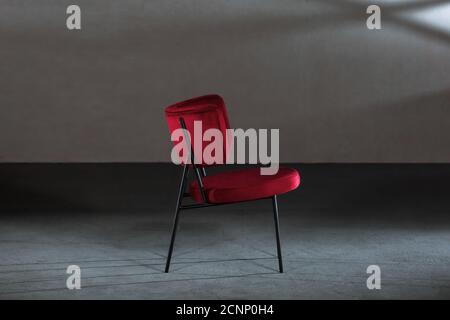 Bequemer roter Ohrensessel in einem Studio mit grauen Wänden Stockfoto