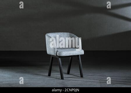 Bequemer weißer Ohrensessel in einem Studio mit grauen Wänden Stockfoto