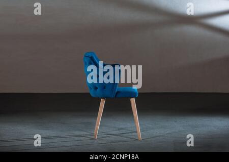 Bequemer blauer Ohrensessel in einem Studio mit grauen Wänden Stockfoto