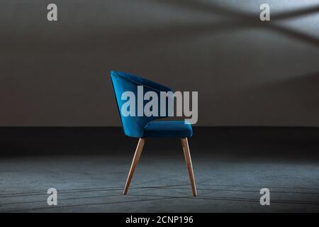 Bequemer blauer Ohrensessel in einem Studio mit grauen Wänden Stockfoto