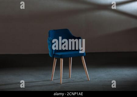 Bequemer blauer Ohrensessel in einem Studio mit grauen Wänden Stockfoto