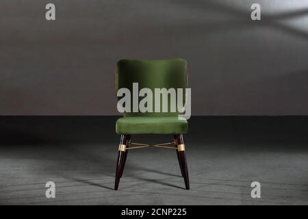 Gemütlicher grüner Ohrensessel in einem Studio mit grauen Wänden Stockfoto