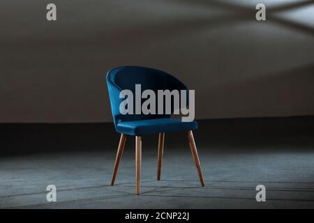 Bequemer blauer Ohrensessel in einem Studio mit grauen Wänden Stockfoto