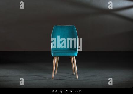 Bequemer blauer Ohrensessel in einem Studio mit grauen Wänden Stockfoto