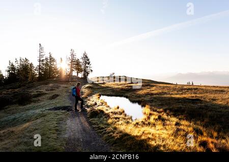 Frau, die morgens am Wasserloch auf dem Rossbrand-Gipfel steht, Österreich Stockfoto