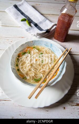 Draufsicht auf Thukpa, eine tibetische Delikatesse in einer Schüssel und Essstäbchen auf einem weißen Teller mit Gewürzen auf einem Hintergrund. Stockfoto