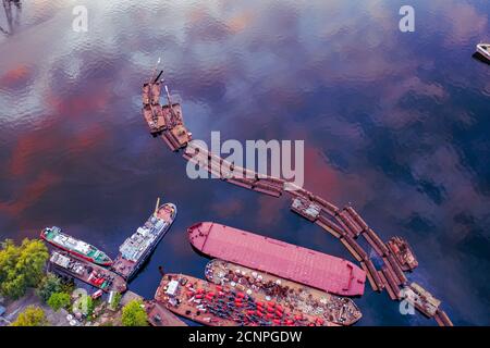 Abstrakte Kunst industriellen Hintergrund mit Copy Space. Verlassene Pier und Boote mit Spiegelung des Himmels im Wasser. Luftaufnahme der Drohne aus nächster Nähe. Stockfoto