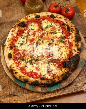 Pizza Margarita oder Margherita mit Tomaten, Mozzarella-Käse, Tomatensauce und Basilikum. Traditionelle Napoletana Pizza auf Holztisch Stockfoto