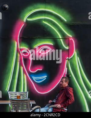 Glasgow, Schottland, Großbritannien. September 2020. Ein Kunde sitzt neben einem neuen Wandbild an der Außenseite der Clutha Bar. Eine Gruppe von Künstlern wurde von der Street Art Group Art Pistol ausgewählt, um neue Wandgemälde an der Fassade der berühmten Bar in Glasgow zu schaffen. Kredit: Skully/Alamy Live Nachrichten Stockfoto