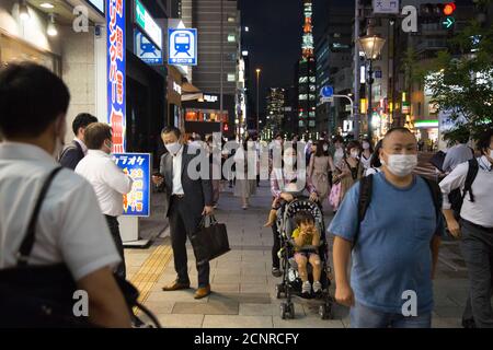 Menschen gehen durch die Straßen, während sie Gesichtsmasken tragen, um sie zu verhüten. Stockfoto