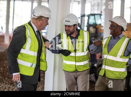 Premierminister Boris Johnson stößt mit Bauarbeitern auf die Ellbogen, als er die Baustelle des neuen Vaccines Manufacturing and Innovation Center (VMIC) besucht, das derzeit auf dem Harwell Science and Innovations Campus in der Nähe von Didcot gebaut wird. Das Gebäude wird für die Herstellung von Impfstoffen für Covid-19 gebaut und soll im nächsten Sommer eröffnet werden. Stockfoto