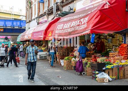 Traditionelle Obst-und Gemüsehändler Shop mit produzieren auf dem Display und Kunden auf Electric Avenue, Brixton, London, England, Vereinigtes Königreich Stockfoto