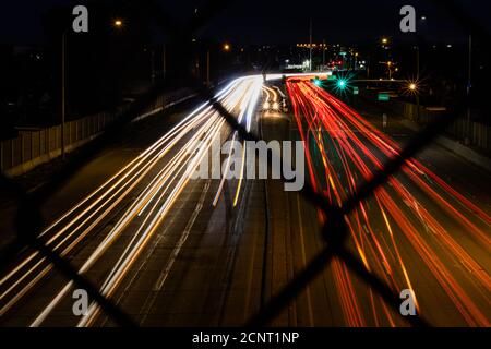 Lange Belichtung einer Autobahn mit Einzäunung im Vordergrund Stockfoto
