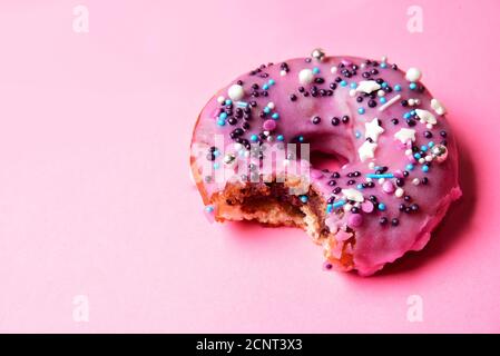 Gebissen rosa Donut mit einem festlichen Pulver. Stockfoto