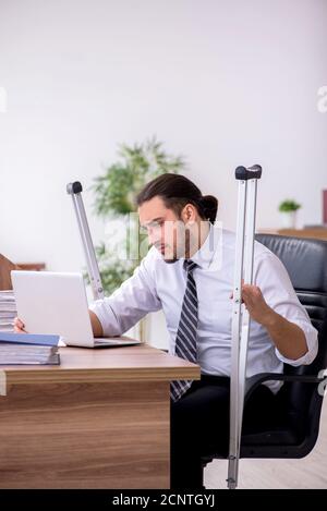 Am Arbeitsplatz erkrankt ein junger, am Bein verletzter Mitarbeiter Stockfoto