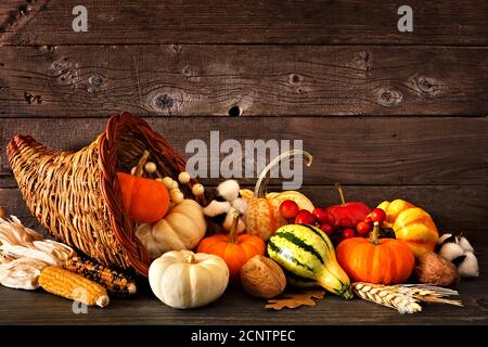 Thanksgiving Füllhorn gefüllt mit Herbstkürbissen und Gemüse gegen ein Rustikale dunkle Holz Hintergrund Stockfoto