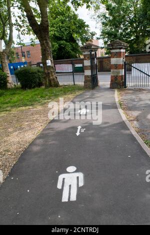 Ein Schild, das in einem Londoner Park auf den Boden gemalt wurde, zeigt die zwei-Meter-Regel an, der die Menschen während der Covid-19-Pandemie 2020 gehorchen mussten. Stockfoto