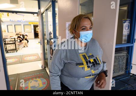 Rio Bravo, Texas USA 17. September 2020: Assistenzleiterin Joanna Navarro schaut auf den Haupteingang der Salvador Garcia Mittelschule in Colonia Rio Bravo bei Laredo entlang der texanischen Grenze zu Mexiko. Navarro hilft Mitarbeitern und Studenten, sich auf den Beginn des persönlichen Unterrichts nächste Woche vorzubereiten. Stockfoto