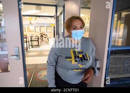 Rio Bravo, Texas USA 17. September 2020: Assistenzleiterin Joanna Navarro schaut auf den Haupteingang der Salvador Garcia Mittelschule in Colonia Rio Bravo bei Laredo entlang der texanischen Grenze zu Mexiko. Navarro hilft Mitarbeitern und Studenten, sich auf den Beginn des persönlichen Unterrichts nächste Woche vorzubereiten. Stockfoto