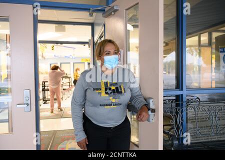 Rio Bravo, Texas USA 17. September 2020: Assistenzleiterin Joanna Navarro schaut auf den Haupteingang der Salvador Garcia Mittelschule in Colonia Rio Bravo bei Laredo entlang der texanischen Grenze zu Mexiko. Navarro hilft Mitarbeitern und Studenten, sich auf den Beginn des persönlichen Unterrichts nächste Woche vorzubereiten. Stockfoto