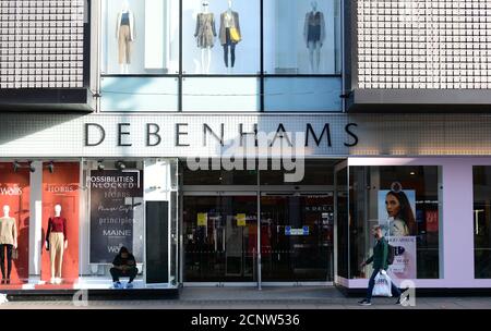 Geschlossene Eingangstüren zum Debenhams Kaufhaus in der Oxford Street, im Zentrum von London, vor der Öffnungszeiten, mit Mitarbeitern im Laden, die Innenfenster putzen und an der Fußgängerzone vorbeigehen, 18. September 2020. Stockfoto