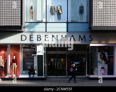 Geschlossene Eingangstüren zum Debenhams Kaufhaus in der Oxford Street, im Zentrum von London, vor der Öffnungszeiten, mit Mitarbeitern im Laden, die Innenfenster putzen und an der Fußgängerzone vorbeigehen, 18. September 2020. Stockfoto