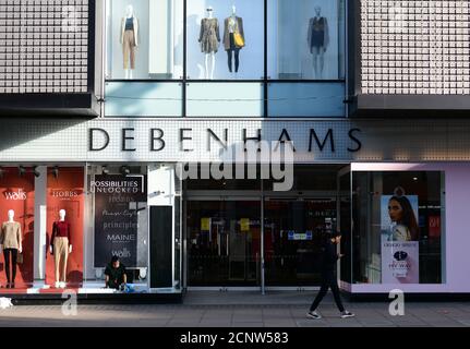 Geschlossene Eingangstüren zum Debenhams Kaufhaus in der Oxford Street, im Zentrum von London, vor der Öffnungszeiten, mit Mitarbeitern im Laden, die Innenfenster putzen und an der Fußgängerzone vorbeigehen, 18. September 2020. Stockfoto