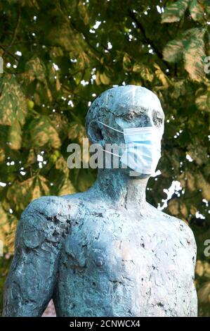 Ein Detail der Dorset Martyrs Skulptur von Dame Elizabeth Frink, zeigt eine Statue mit einer chirurgischen Gesichtsmaske während der Covid 19 Pandemie. England. Stockfoto