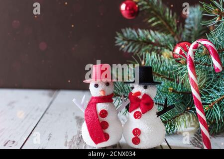 Ein paar Schneemänner stehen auf Holzboden in der Nähe von Weihnachtsbaum. Frohe Weihnachten und Glückwünsche zum neuen Jahr. Stockfoto