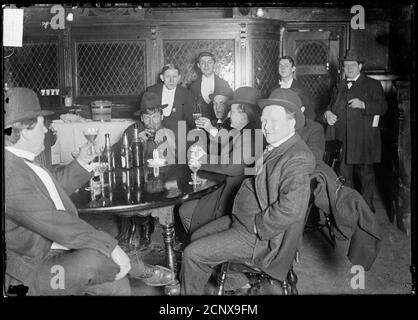 Interieur des Salons mit sechs Männern, die um einen Tisch sitzen und Alkohol trinken, Chicago, Illinois, um 1905. Stockfoto