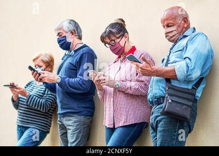 Ältere Menschen mit Smartphones mit Gesichtsmaske auf - alt Mann im Fokus Stockfoto