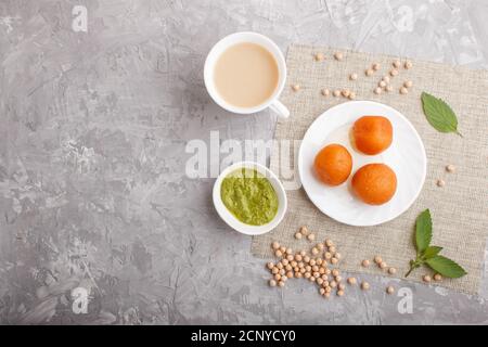 Traditionelle indische Süßigkeiten Gulab Jamun in weißem Teller mit Minze Chutney auf einem grauen Beton Hintergrund. Draufsicht, Kopierraum, flach legen. Stockfoto