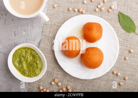 Traditionelle indische Süßigkeiten Gulab jamun in weißem Teller mit Minze Chutney auf einem grauen Beton Hintergrund. Draufsicht, flache Lage. Nahaufnahme. Stockfoto