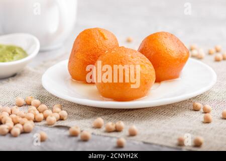 Traditionelle indische Süßigkeiten Gulab Jamun in weißem Teller mit Minze Chutney auf einem grauen Beton Hintergrund. Seitenansicht, close up. Stockfoto