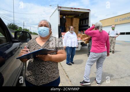 El Cenizo, TX USA 17. September 2020: Lokale Freiwillige verteilen Lebensmittelkisten an Bewohner der colonia von El Cenizo etwa 10 Meilen südlich von Laredo entlang der Texas-Mexiko-Grenze. Etwa 450 Familien werden zweimal in der Woche mit Heftklammern und frischem Obst in einer von der lateinamerikanischen lutherischen Mission (LALM) gesponserten Bemühung serviert. Aufgrund der Coronavirus-Pandemie ist die Verteilung nun ein sozial distanziertes Drive-Through-Ereignis, bei dem Freiwillige und Kunden alle Gesichtsbezüge tragen. Kredit: Bob Daemmrich/Alamy Live Nachrichten Stockfoto