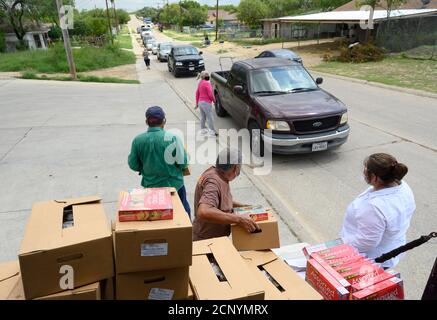 El Cenizo, TX USA 17. September 2020: Lokale Freiwillige verteilen Lebensmittelkisten an Bewohner der colonia von El Cenizo etwa 10 Meilen südlich von Laredo entlang der Texas-Mexiko-Grenze. Etwa 450 Familien werden zweimal in der Woche mit Heftklammern und frischem Obst in einer von der lateinamerikanischen lutherischen Mission (LALM) gesponserten Bemühung serviert. Aufgrund der Coronavirus-Pandemie ist die Verteilung nun ein sozial distanziertes Drive-Through-Ereignis, bei dem Freiwillige und Kunden alle Gesichtsbezüge tragen. Kredit: Bob Daemmrich/Alamy Live Nachrichten Stockfoto