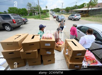 El Cenizo, TX USA 17. September 2020: Lokale Freiwillige verteilen Lebensmittelkisten an Bewohner der colonia von El Cenizo etwa 10 Meilen südlich von Laredo entlang der Texas-Mexiko-Grenze. Etwa 450 Familien werden zweimal in der Woche mit Heftklammern und frischem Obst in einer von der lateinamerikanischen lutherischen Mission (LALM) gesponserten Bemühung serviert. Aufgrund der Coronavirus-Pandemie ist die Verteilung nun ein sozial distanziertes Drive-Through-Ereignis, bei dem Freiwillige und Kunden alle Gesichtsbezüge tragen. Kredit: Bob Daemmrich/Alamy Live Nachrichten Stockfoto