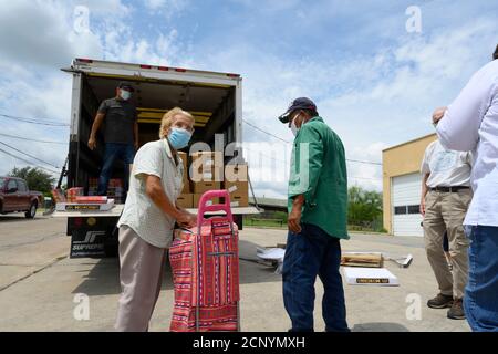 El Cenizo, TX USA 17. September 2020: Lokale Freiwillige verteilen Lebensmittelkisten an Bewohner der colonia von El Cenizo etwa 10 Meilen südlich von Laredo entlang der Texas-Mexiko-Grenze. Etwa 450 Familien werden zweimal in der Woche mit Heftklammern und frischem Obst in einer von der lateinamerikanischen lutherischen Mission (LALM) gesponserten Bemühung serviert. Aufgrund der Coronavirus-Pandemie ist die Verteilung nun ein sozial distanziertes Drive-Through-Ereignis, bei dem Freiwillige und Kunden alle Gesichtsbezüge tragen. Kredit: Bob Daemmrich/Alamy Live Nachrichten Stockfoto