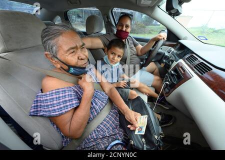 El Cenizo, TX USA 17. September 2020: Eine lokale Familie wartet im Auto, während Freiwillige Lebensmittelkisten an Bewohner der colonia von El Cenizo verteilen, 10 Meilen südlich von Laredo entlang der Texas-Mexiko-Grenze. Etwa 450 Familien werden zweimal in der Woche mit Heftklammern und frischem Obst in einer von der lateinamerikanischen lutherischen Mission (LALM) gesponserten Bemühung serviert. Aufgrund der Coronavirus-Pandemie ist die Verteilung nun ein sozial distanziertes Drive-Through-Ereignis, bei dem Freiwillige und Kunden alle Gesichtsbezüge tragen. Kredit: Bob Daemmrich/Alamy Live Nachrichten Stockfoto