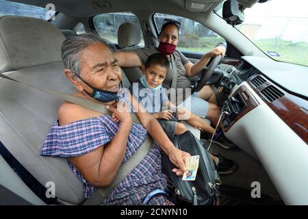 El Cenizo, TX USA 17. September 2020: Eine lokale Familie wartet im Auto, während Freiwillige Lebensmittelkisten an Bewohner der colonia von El Cenizo verteilen, 10 Meilen südlich von Laredo entlang der Texas-Mexiko-Grenze. Etwa 450 Familien werden zweimal in der Woche mit Heftklammern und frischem Obst in einer von der lateinamerikanischen lutherischen Mission (LALM) gesponserten Bemühung serviert. Aufgrund der Coronavirus-Pandemie ist die Verteilung nun ein sozial distanziertes Drive-Through-Ereignis, bei dem Freiwillige und Kunden alle Gesichtsbezüge tragen. Kredit: Bob Daemmrich/Alamy Live Nachrichten Stockfoto