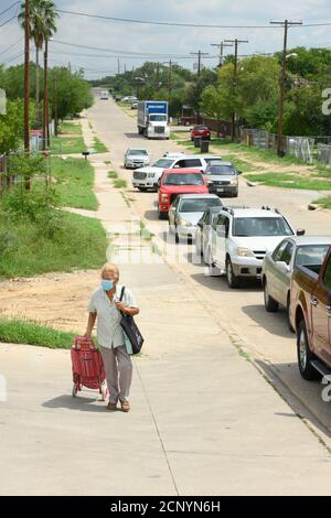 El Cenizo, TX USA 17. September 2020: Eine Frau mit einem Einkaufswagen geht zu einem Drive-up Foor Distribution Site für Bewohner der colonia von El Cenizo 10 Meilen südlich von Laredo entlang der Texas-Mexiko-Grenze. Etwa 450 Familien werden zweimal in der Woche mit Heftklammern und frischem Obst in einer von der lateinamerikanischen lutherischen Mission (LALM) gesponserten Bemühung serviert. Aufgrund der Coronavirus-Pandemie ist die Verteilung nun (meist) ein sozial distanziertes Drive-Through-Ereignis, bei dem Freiwillige und Kunden alle Gesichtsbezüge tragen. Kredit: Bob Daemmrich/Alamy Live Nachrichten Stockfoto