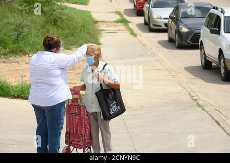 El Cenizo, TX USA 17. September 2020: Lokale Freiwillige PR. Maria Mendez segnet einen bewalkten Klienten, während sie und andere Freiwillige Lebensmittelkisten an Bewohner der colonia von El Cenizo verteilen, 10 Meilen südlich von Laredo entlang der Texas-Mexiko-Grenze. Etwa 450 Familien werden zweimal in der Woche mit Heftklammern und frischem Obst in einer von der lateinamerikanischen lutherischen Mission (LALM) gesponserten Bemühung serviert. Aufgrund der Coronavirus-Pandemie ist die Verteilung nun (meist) ein sozial distanziertes Drive-Through-Ereignis, bei dem Freiwillige und Kunden alle Gesichtsbezüge tragen. Kredit: Bob Daemmrich/Alamy Live Nachrichten Stockfoto